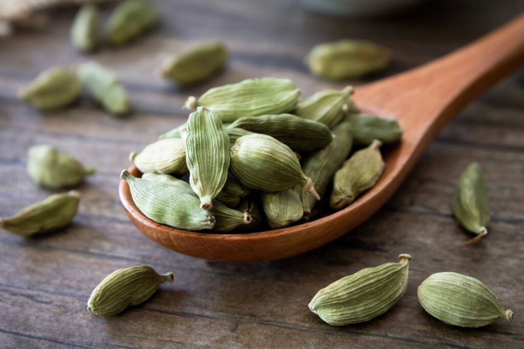 Cardamom pods on a wooden spoon