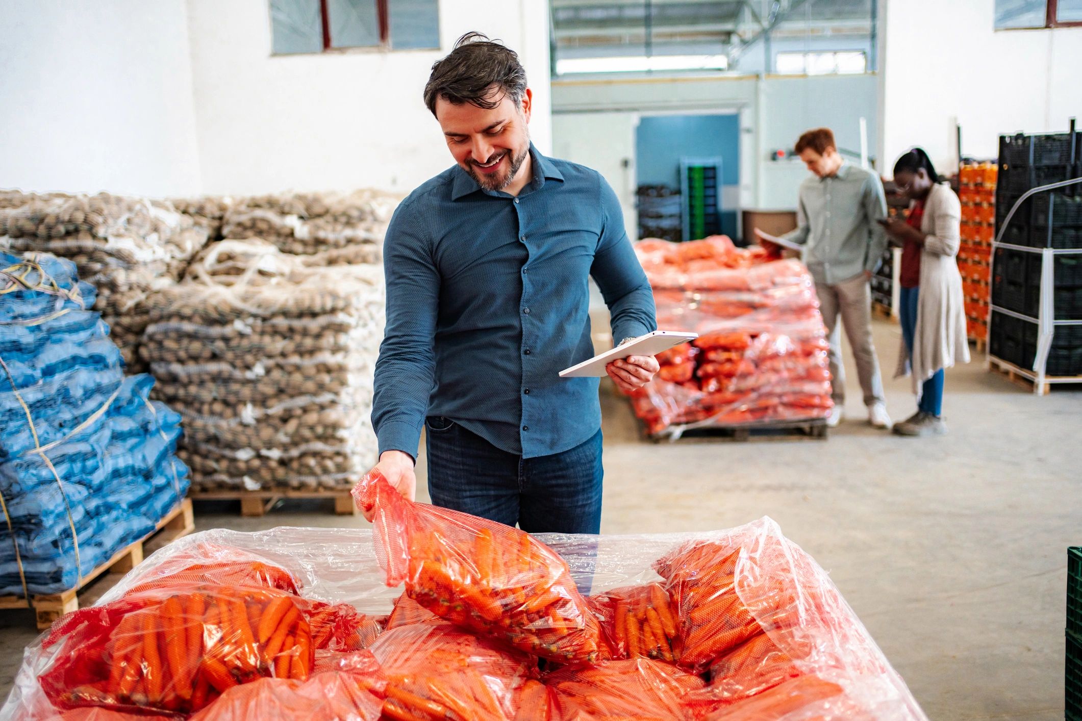 Warehouse manager checking fresh carrots with digital tablet